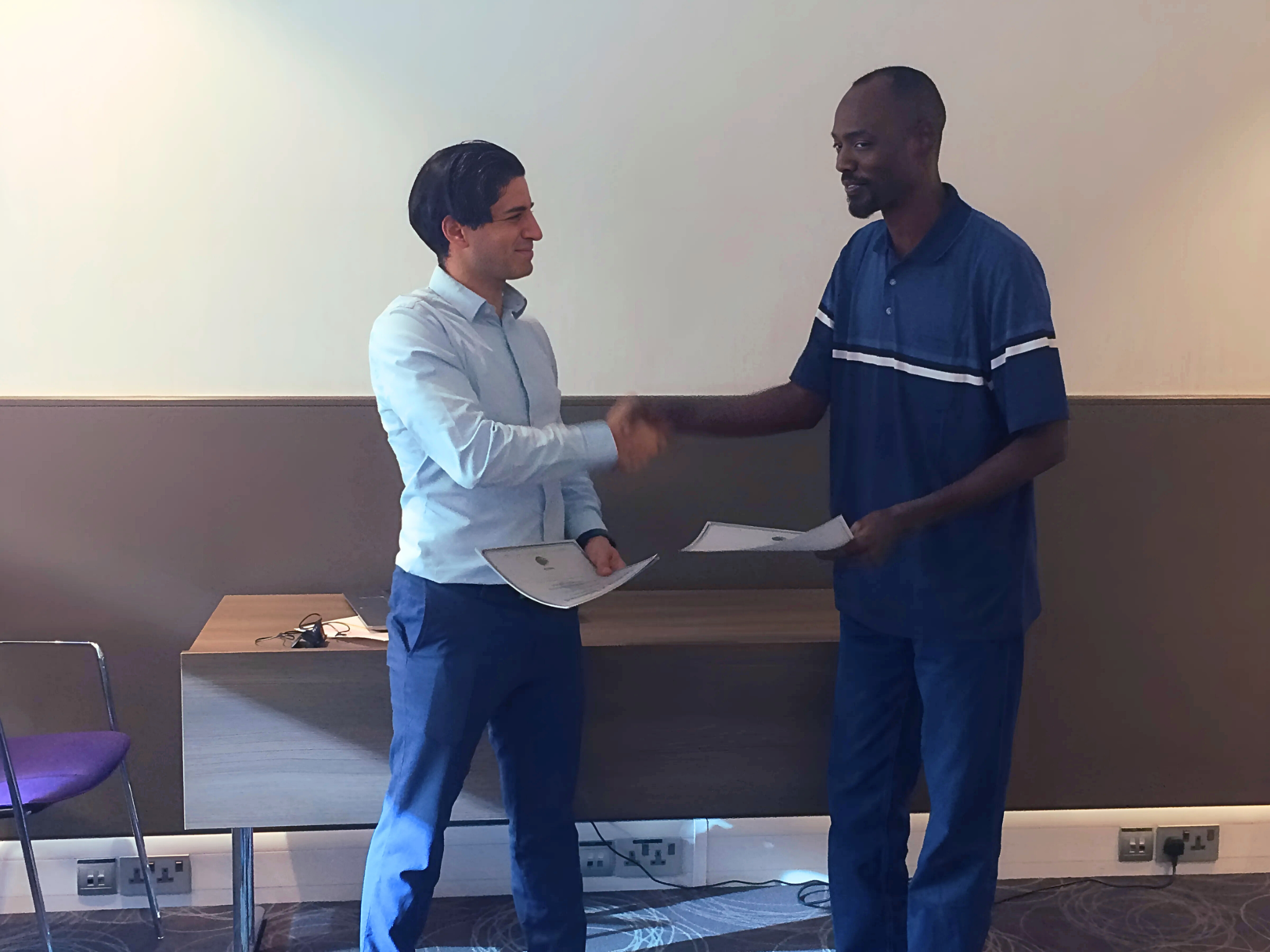 Basim Mousilli shaking hands and presenting a certificate