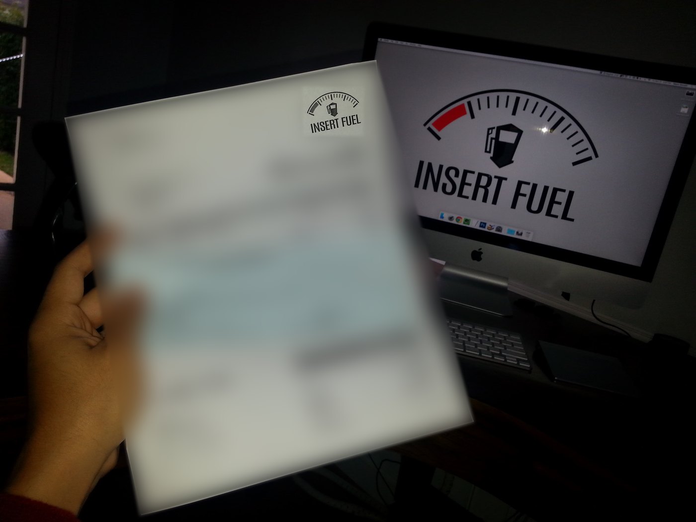 Basim holding Insert Fuel's first client check in front of a screen showing the Insert Fuel logo
