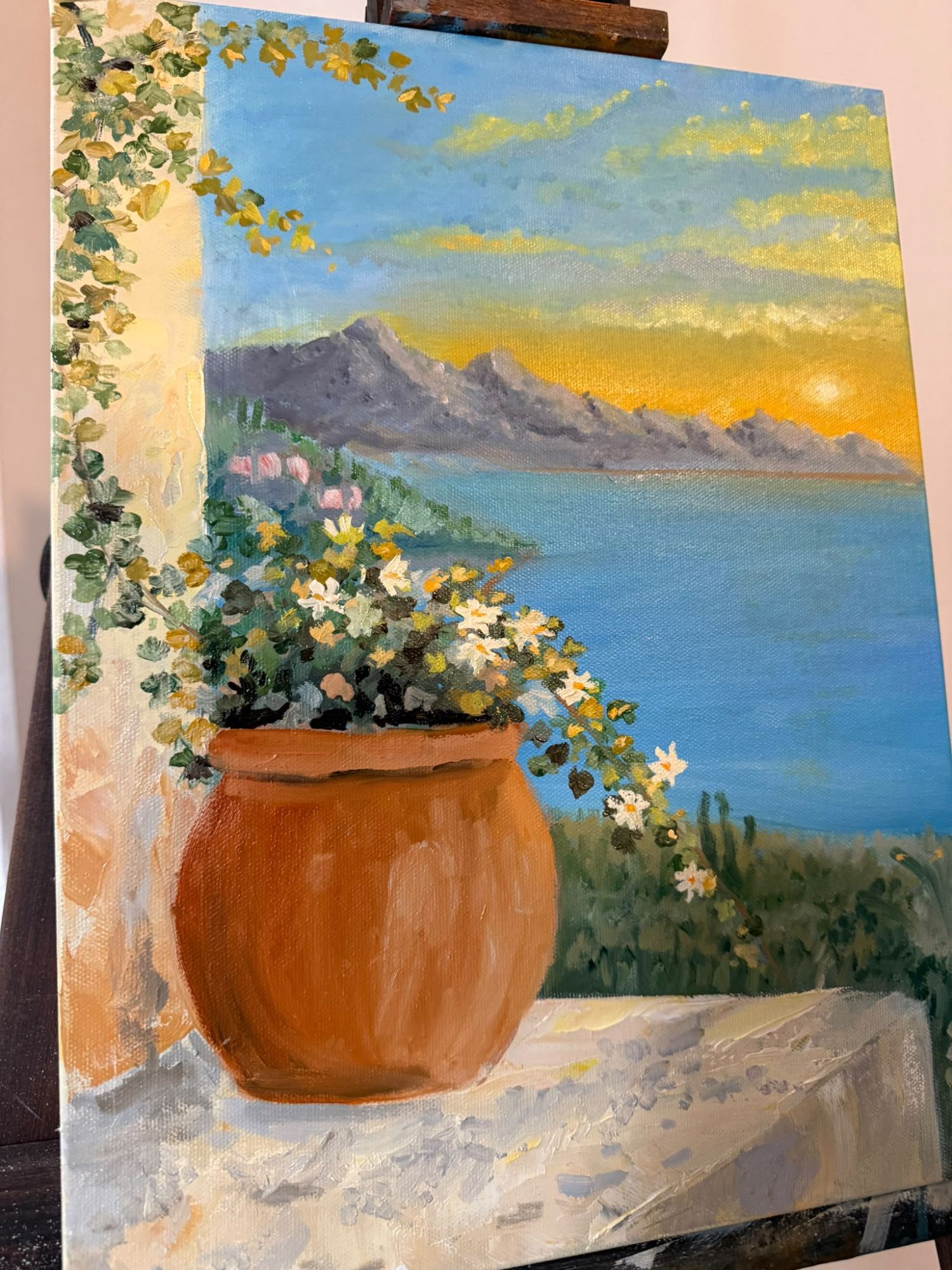 Oil painting of a terrace at sunset with a pot of white flowers, a vine and mountains over the sea